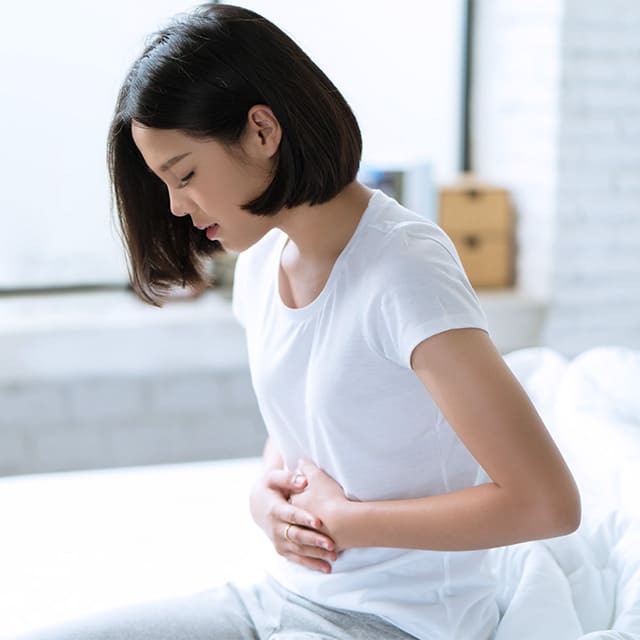 胃を押さえる女性